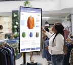 African american client selecting items to buy from self service checkout kiosk, reviewing modern clothes and sizes on interactive monitor. Young woman looking at products on board.