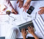 engineers pointing to building on blueprint and using laptop to drawing design building Project in office, construction concept. Engineer concept